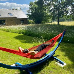 a man laying in a hammock in a yard at Une maison à la campagne in Saint-Mars-sur-la-Futaie