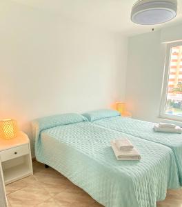 a bedroom with a bed with blue sheets and a window at Apartamento Luz del Mar in Torrox Costa