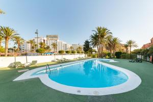Una gran piscina con palmeras y edificios. en Las Buganvillas, en Roquetas de Mar
