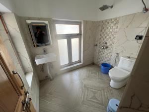 a bathroom with a toilet and a sink and a window at sky land in Leh