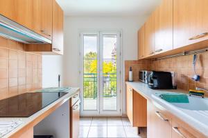 eine Küche mit Holzschränken und einem großen Fenster in der Unterkunft GuestReady - Havre de Paix à Courbevoie in La Défense