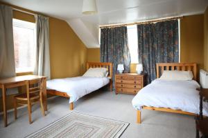 1 Schlafzimmer mit 2 Betten, einem Schreibtisch und Fenstern in der Unterkunft Convenient and stylish cottage in Abergavenny