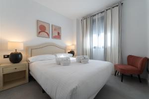 sypialnia z białym łóżkiem i czerwonym krzesłem w obiekcie Estepona Holiday Hills w mieście Estepona
