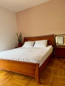 a bedroom with a large bed with a wooden headboard at Apartment Life in Nikšić