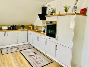 een keuken met witte kasten en een houten vloer bij SWEETHOME am WOOGBACH Speyer in Speyer +44 foto's