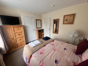 a bedroom with a bed with a television and a dresser at The Northdale Hotel Ltd in Skegness