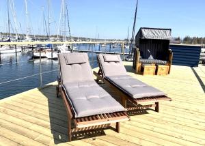 a row of benches sitting on a dock near the water at Hausboot LUMME - Huus & Meer in Großenbrode-Kai