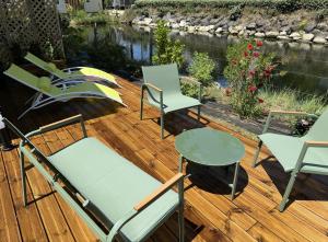a deck with chairs and tables and a river at Mobil home tout confort Camping Les VIVIERS CAP FERRET in Lège-Cap-Ferret