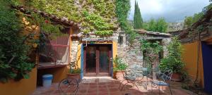 un edificio de piedra con un patio con sillas y plantas en El Mirador de Las Jaras en Patones