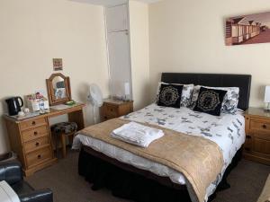 a bedroom with a bed and a desk with a mirror at The Northdale Hotel Ltd in Skegness