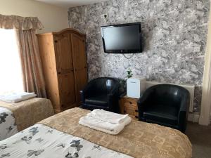 a bedroom with two chairs and a tv on the wall at The Northdale Hotel Ltd in Skegness