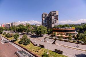 a park with benches and buildings in a city at Шелковый Путь Премиум in Almaty
