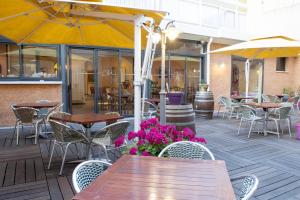 un patio al aire libre con mesas, sillas y flores en Résidence Créole, en Valras-Plage