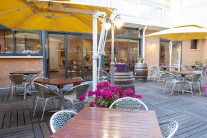 an outdoor patio with tables and chairs and flowers at Résidence Créole in Valras-Plage