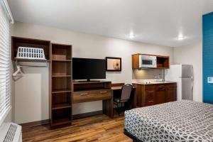 Camera piccola con letto e scrivania con computer. di WoodSpring Suites Port St Lucie a Port Saint Lucie