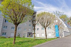 un bâtiment avec des arbres devant lui dans l'établissement Comfort Aparthotel Besancon La City, à Besançon