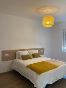 Un dormitorio con una cama grande con una lámpara de araña. en O Mirador Alere Carnota playa, en San Mamede de Carnota