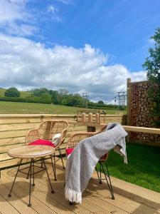a patio with two chairs and a table with a blanket at Coedydd - Woods in Bridgend +16 photos