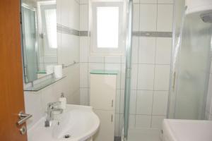 a white bathroom with a sink and a shower at Beachside Babe in Novalja