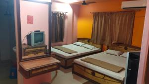 a small room with two beds and a television at Hotel Sunny New Digha Near Sea Beach View Point - Couple Friendly in Digha