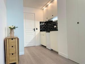 a kitchen with white cabinets and a vase of flowers on a table at Jean Kiffer in Le Plessis-Trévise