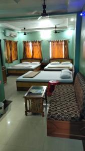 a room with four beds and a couch and a table at Hotel Sunny New Digha Near Sea Beach View Point - Couple Friendly in Digha