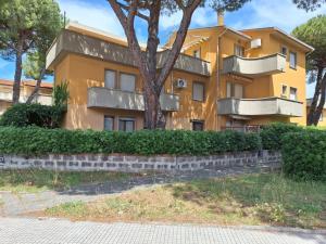 a yellow building with a tree in front of it at Appartamento le vele in Cecina