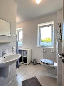 a bathroom with a sink and a toilet and a window at Haus Monika in Dagebüll