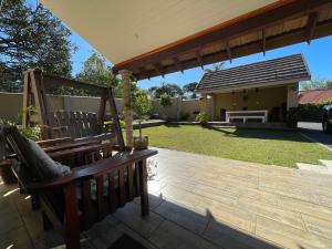 a patio with a wooden bench under a pavilion at OAK HOUSE, Entire holiday home, Self catering, fully equipped, double storey, 3 bedroom, 2 bathroom, outside entertainment, Braai area, 300sqm home in Hillcrest