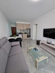 a living room with a couch and a table at Vrexi Apartment - By IMH Travel & Tours in Paphos City +9 photos