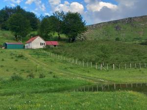 a house on a hill in a field with a fence at Jezerca Wild Beauty in Pluzine