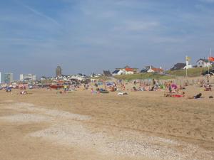 a group of people sitting on a beach at Apartment Ella with free privat parking in Zandvoort