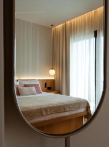 a mirror reflecting a bedroom with a bed and a window at Akti Hotel Kavala in Paleo Tsifliki