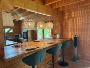 une cuisine avec un grand bar en bois avec des chaises dans l'établissement Chalet dans un écrin de verdure avec SPA privatif, à Jeanménil