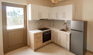 a kitchen with white cabinets and a refrigerator and a window at VAYAL SKYROS in Skiros