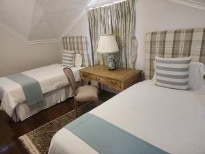 a bedroom with two beds and a table with a lamp at Stone Town Guesthouse in Gaborone +16 photos