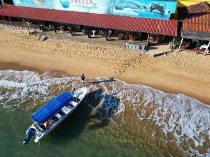 un barco en el agua junto a una playa en Pousada Frezza Mergulho en Praia Vermelha