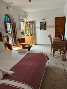 a bedroom with a bed and a table and a desk at Dar Al Miraaj in Rabat