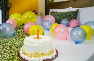 een verjaardagstaart met een kaars op een bed met ballonnen bij Eurotel Pedro Gil in Manilla