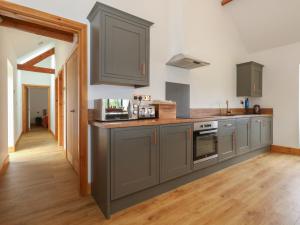 a kitchen with gray cabinets and a wooden floor at Swallows Nest in Sturminster Newton