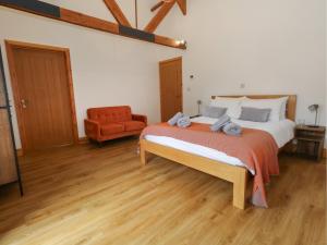 a bedroom with a large bed and a chair at Swallows Nest in Sturminster Newton