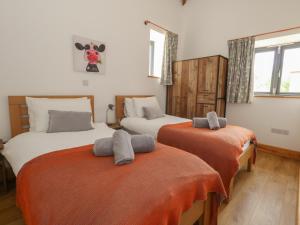 a bedroom with two beds with orange sheets at Swallows Nest in Sturminster Newton +30 photos