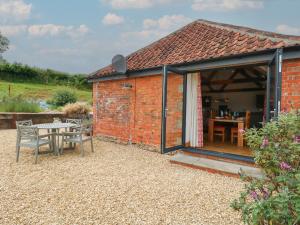 a small red brick building with a table and chairs at Swallows Nest in Sturminster Newton