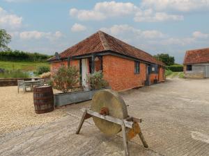a brick building with a wheel in front of it at Swallows Nest in Sturminster Newton