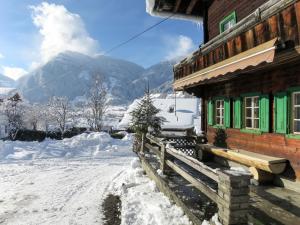a snow covered building with green windows and a mountain at Holiday Home Geislerhütte by Interhome in Ramsau