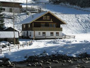 a house in the snow next to a river at Holiday Home Farm Eben by Interhome in Ginzling