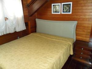 a small bedroom with a bed and two pictures on the wall at Suite No Centro De Gramado in Gramado