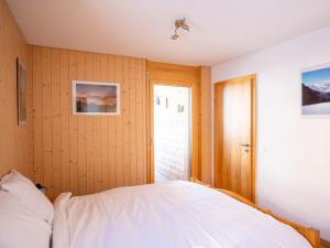 a bedroom with a bed with white sheets and a door at Apartment Les Cîmes 4 by Interhome in Les Collons +15 photos