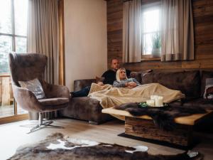 un hombre y una mujer sentados en un sofá en una sala de estar en Holiday Home Waldkauz-1 by Interhome en Pfarrwerfen