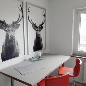 a white desk with two deer prints on the wall at Wiedhöhen Ferienwohnung in Roßbach +16 photos